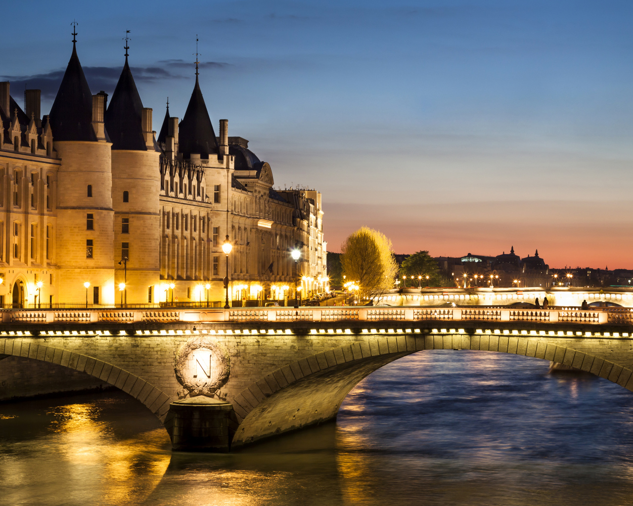 Мост в свете ночных фонарей у бывшего королевского замка Консьержери, Париж. Франция 