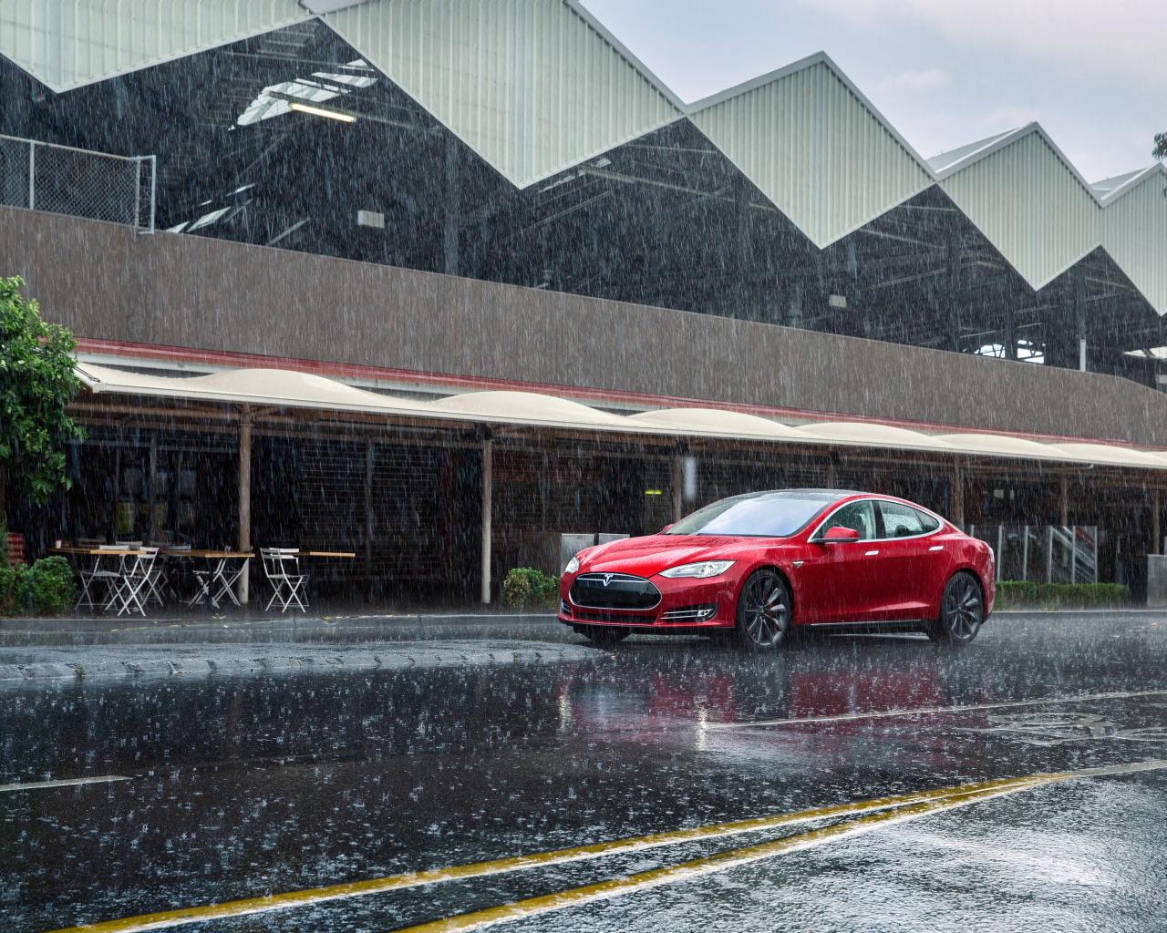 Красный автомобиль  Tesla Model S на дороге под дождем