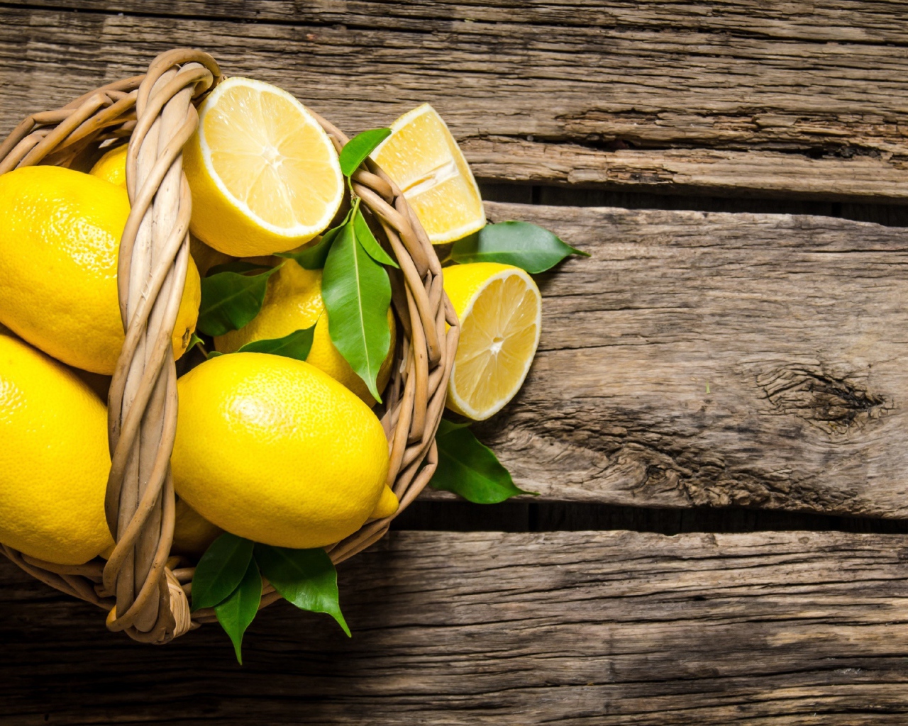 Красивые желтые лимоны в корзине на деревянном столе