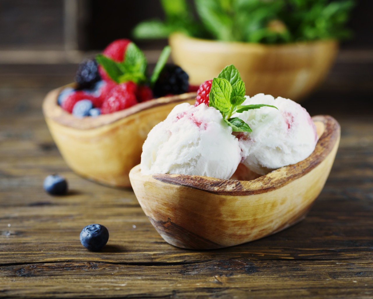 Ice cream balls with berries in a wooden bowl