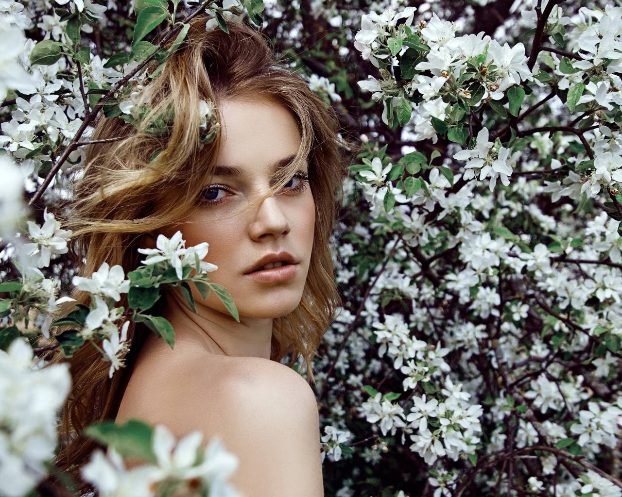 Beautiful girl in the branches of a blossoming apple tree
