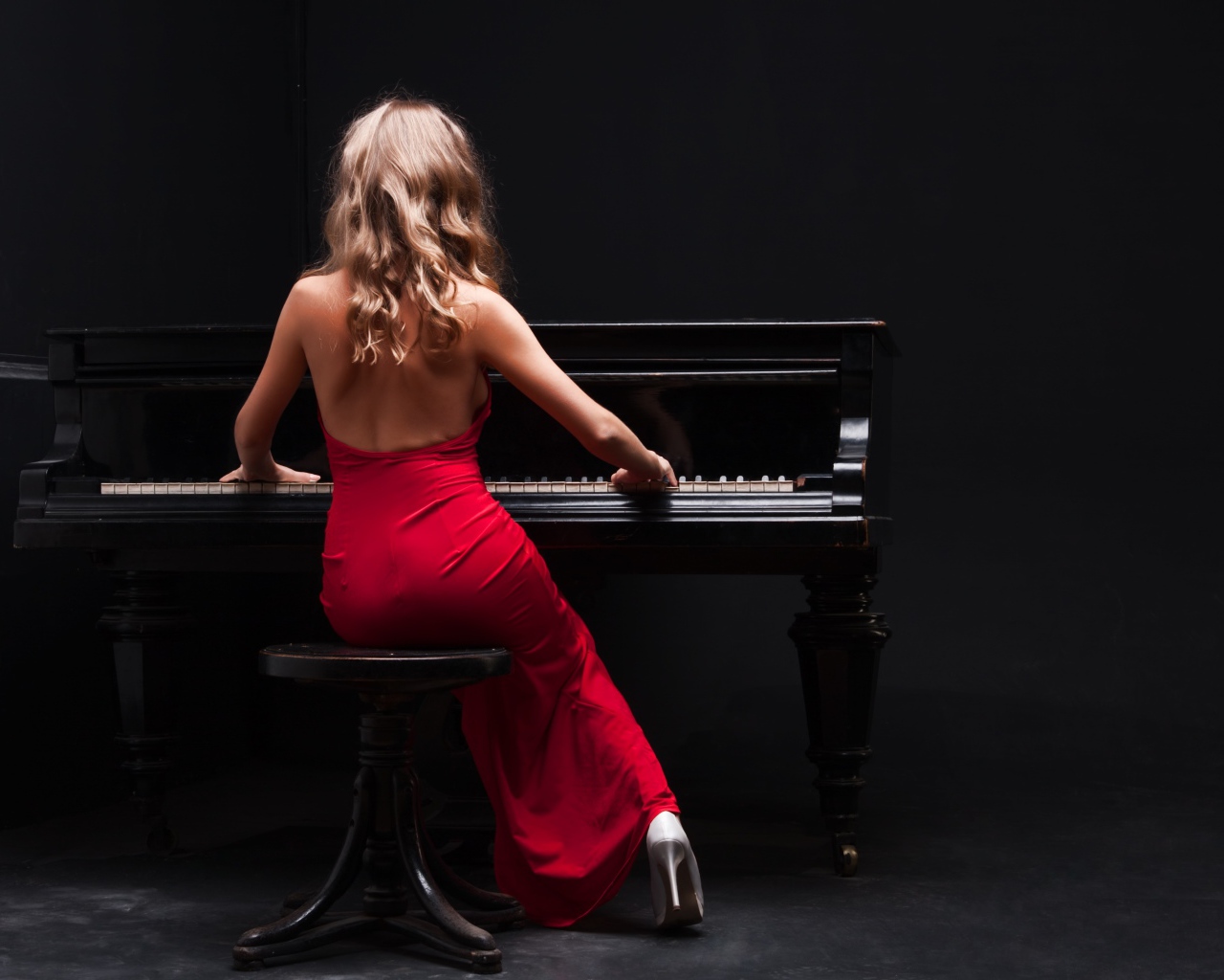 Молодая девушка в красном платье играет на пианино