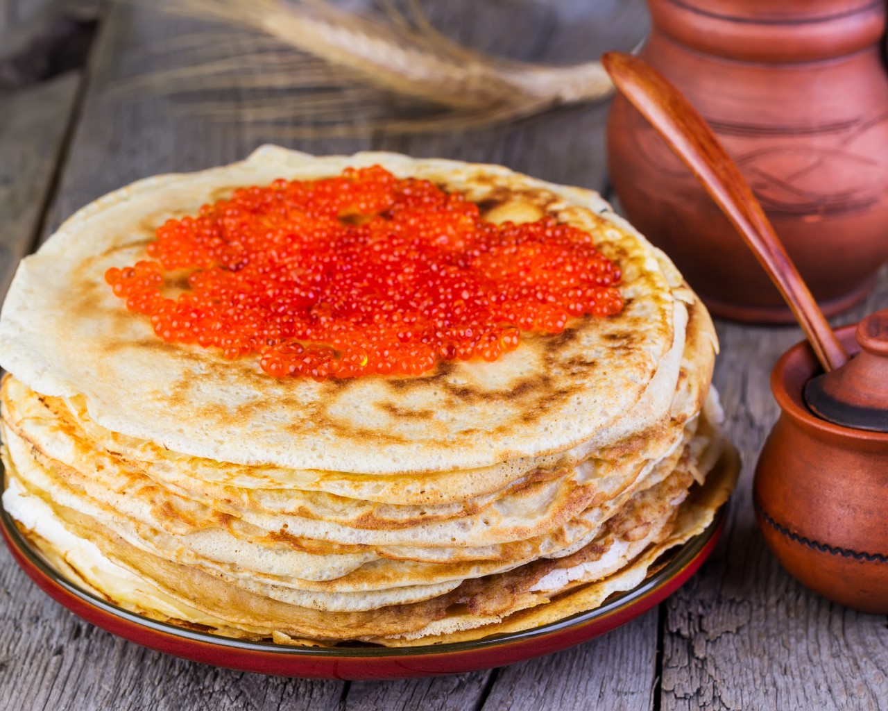 A pile of pancakes with red caviar on a wooden table, a treat for Shrovetide