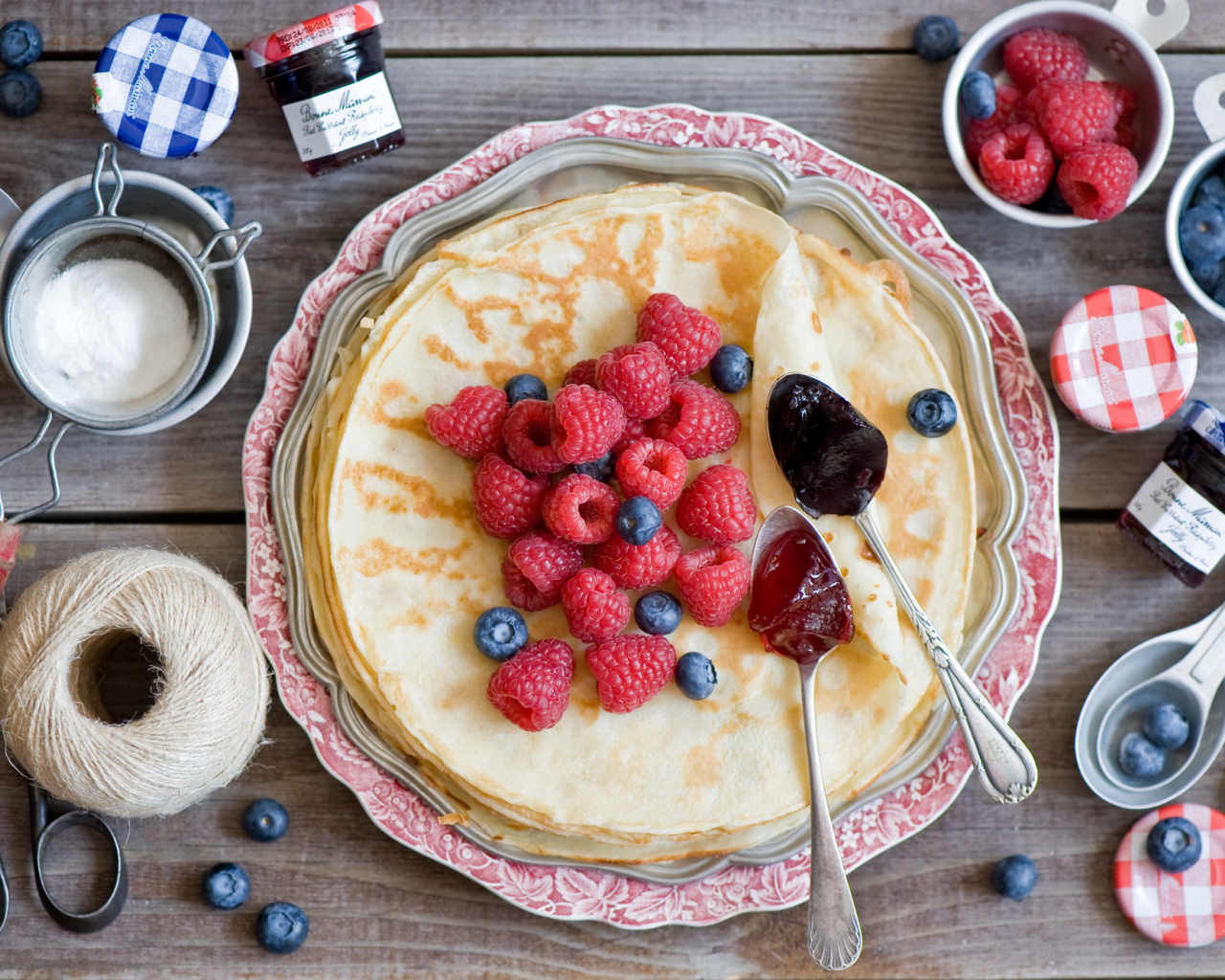 Thin pancakes with raspberries and blueberries on the table top view