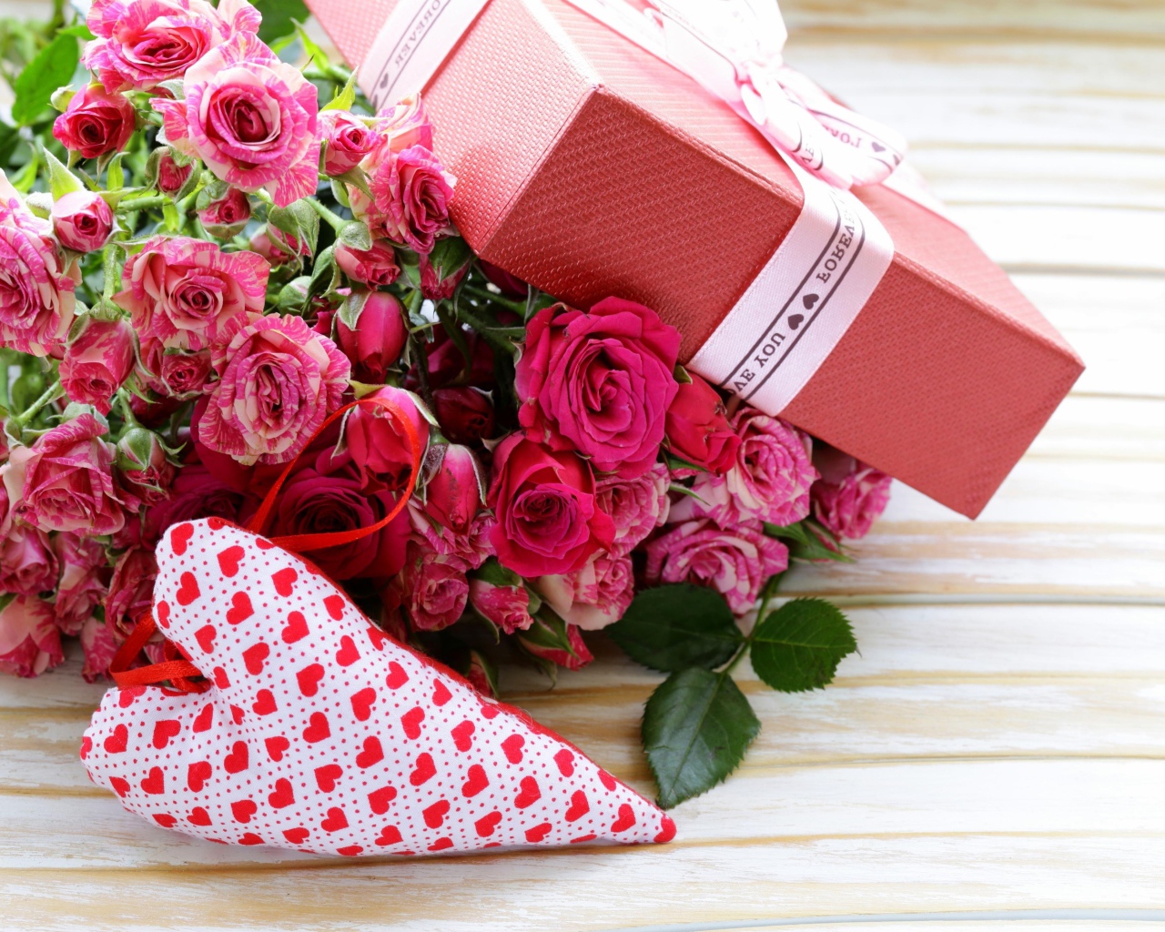 Bouquet of pink roses with a gift and a heart on the table
