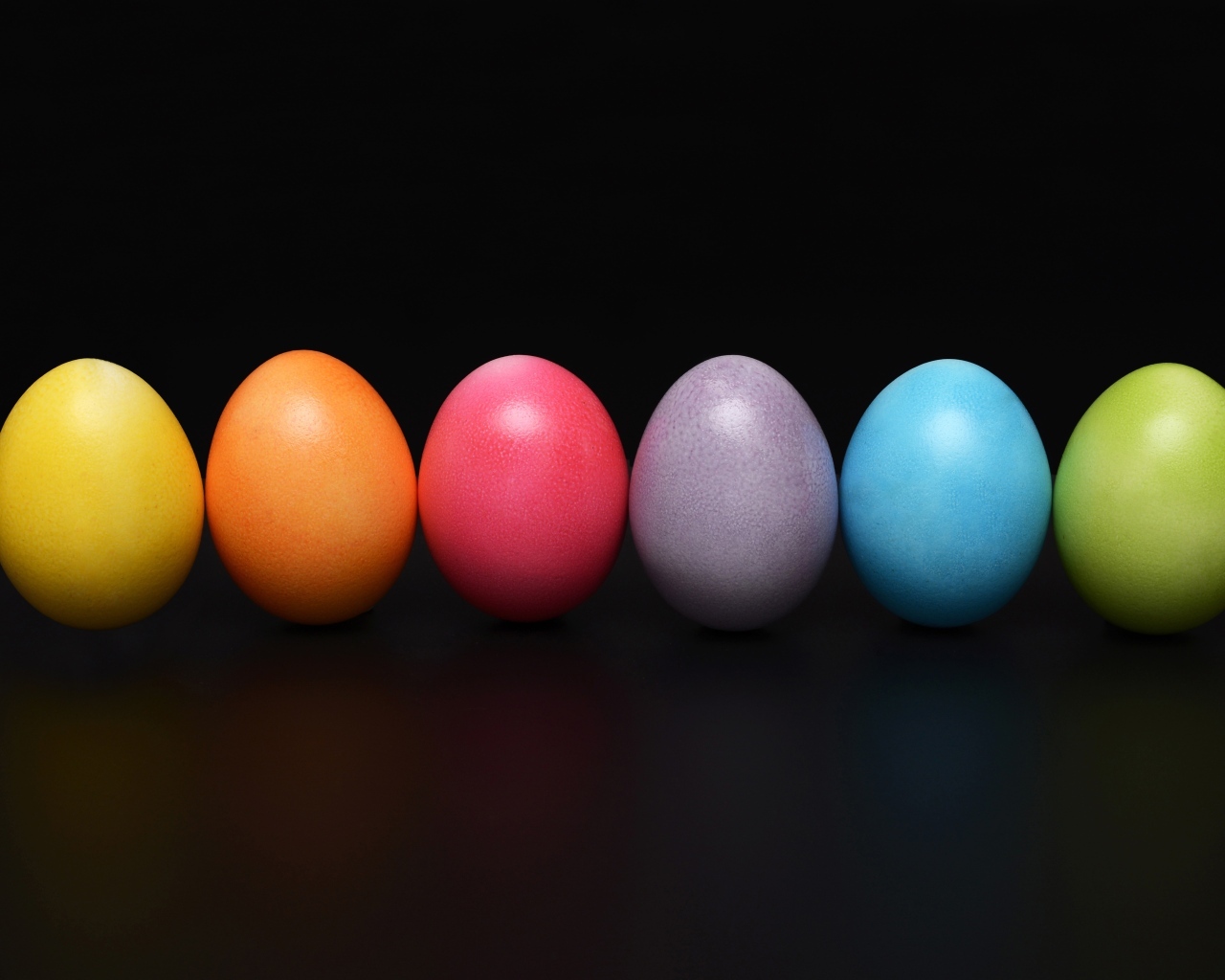 Разноцветные пасхальные яйца на черном фоне