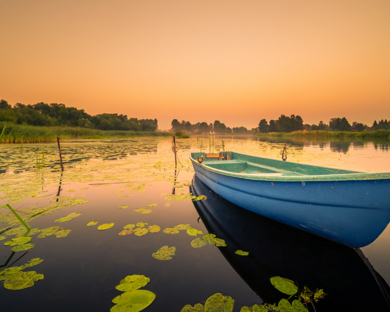 Голубая лодка в озере на закате солнца
