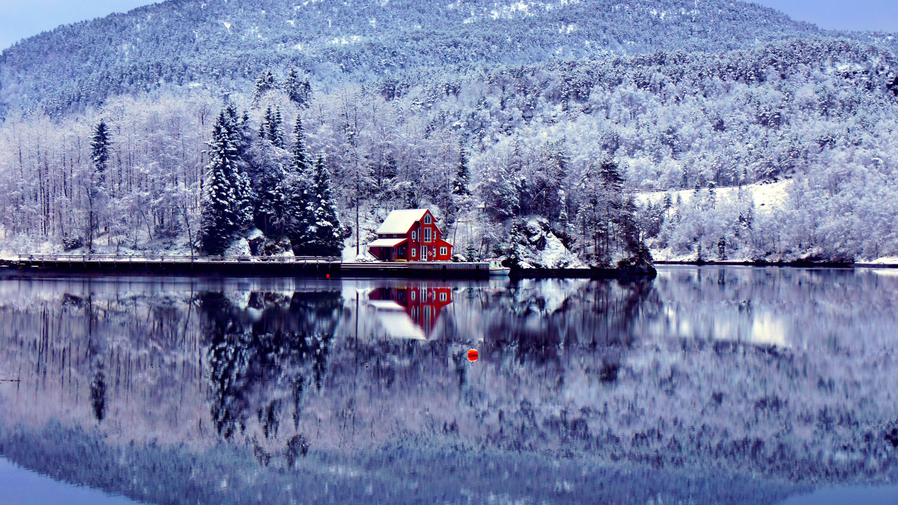 Дом, лес и гора отражают в озере зимой