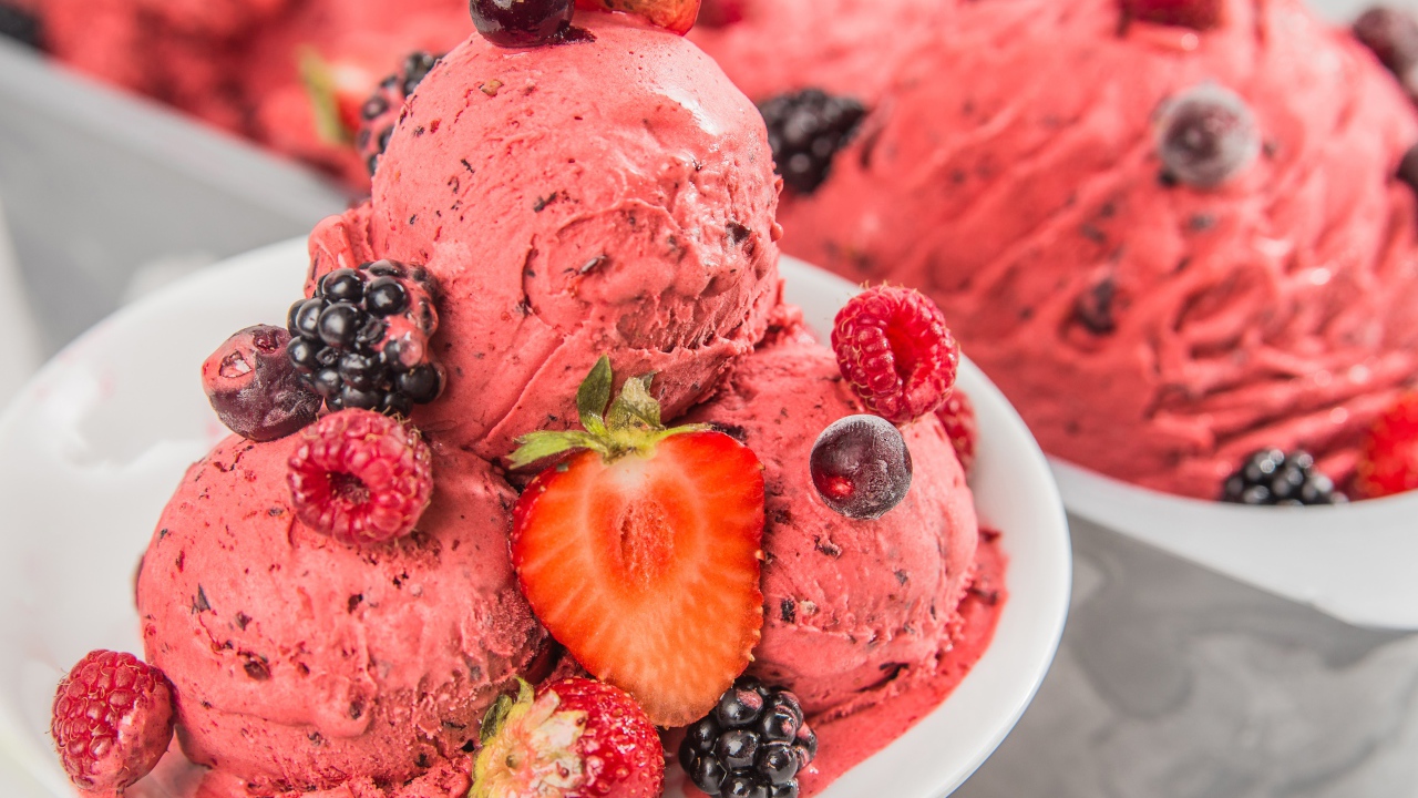 Шарики фруктового мороженого на тарелке с ягодами 