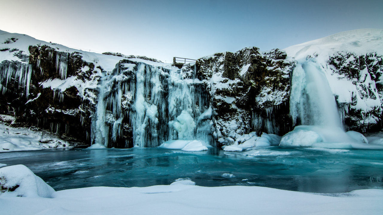 The frozen waterfall drains from the cliff in winter