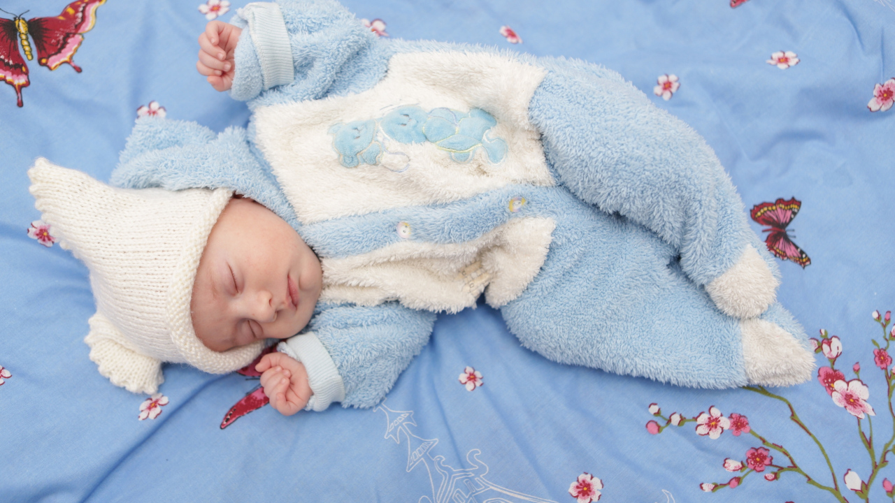 Грудной спящий ребенок в голубом костюме