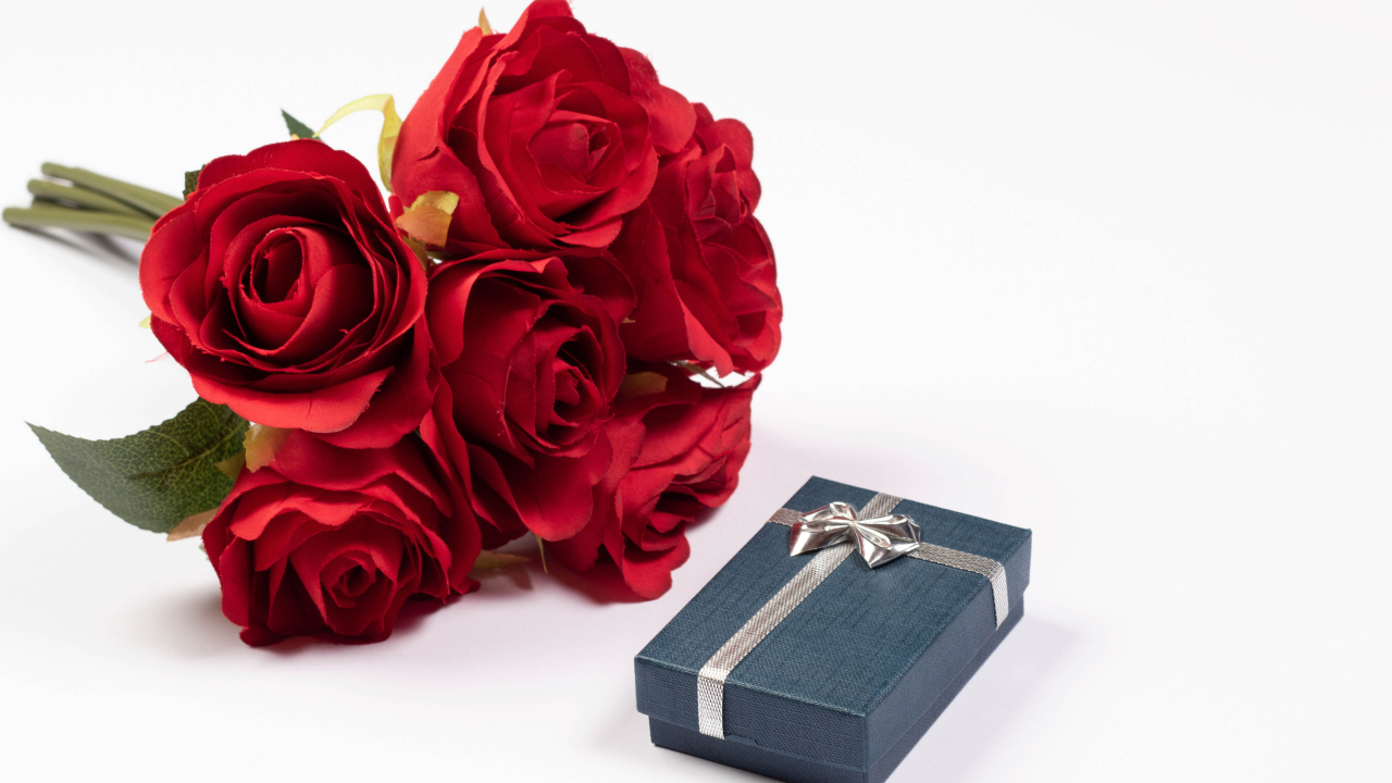 Букет красных искусственных роз с подарком на белом фоне