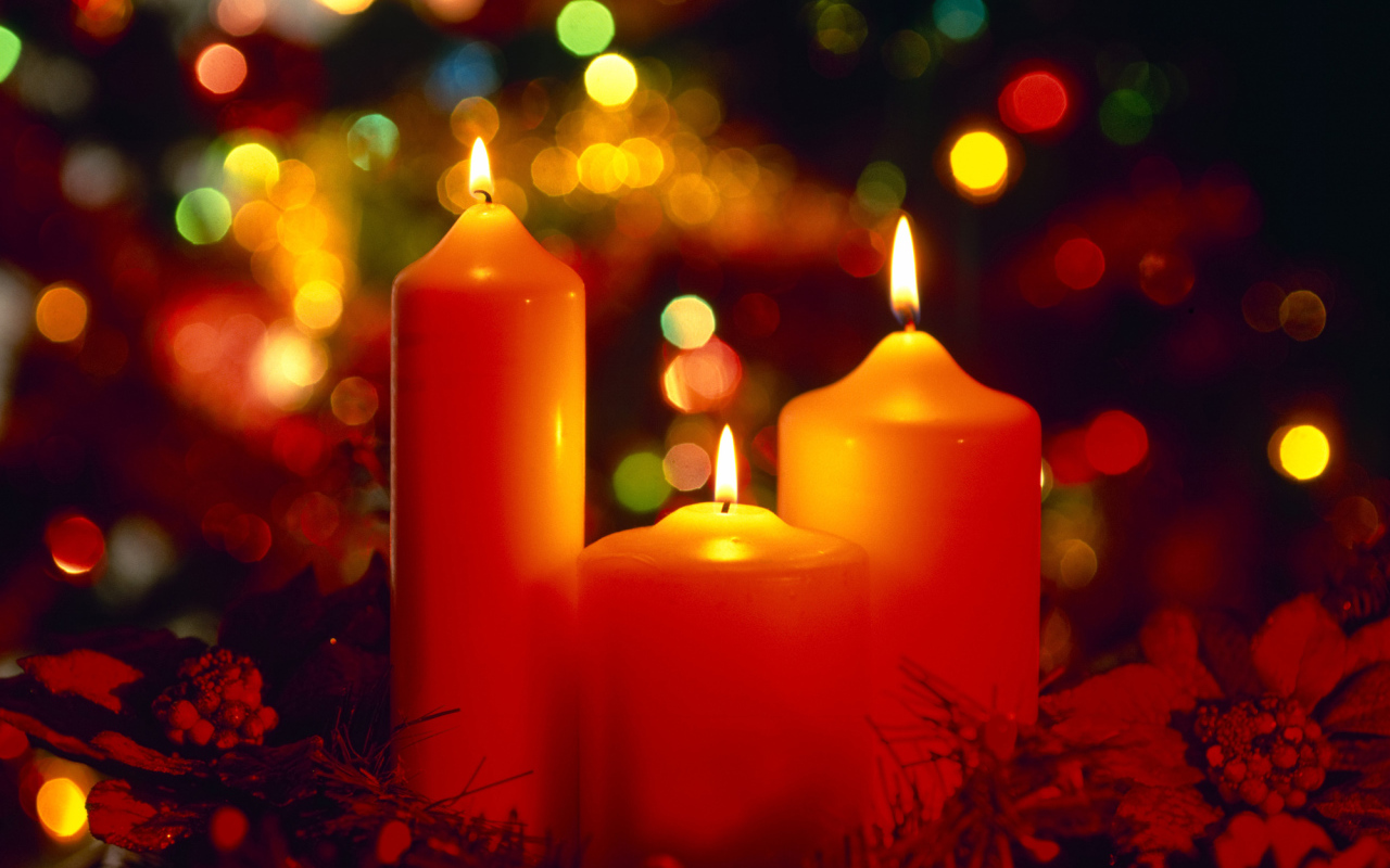 Горящие красные свечи на фоне гирлянды на рождество