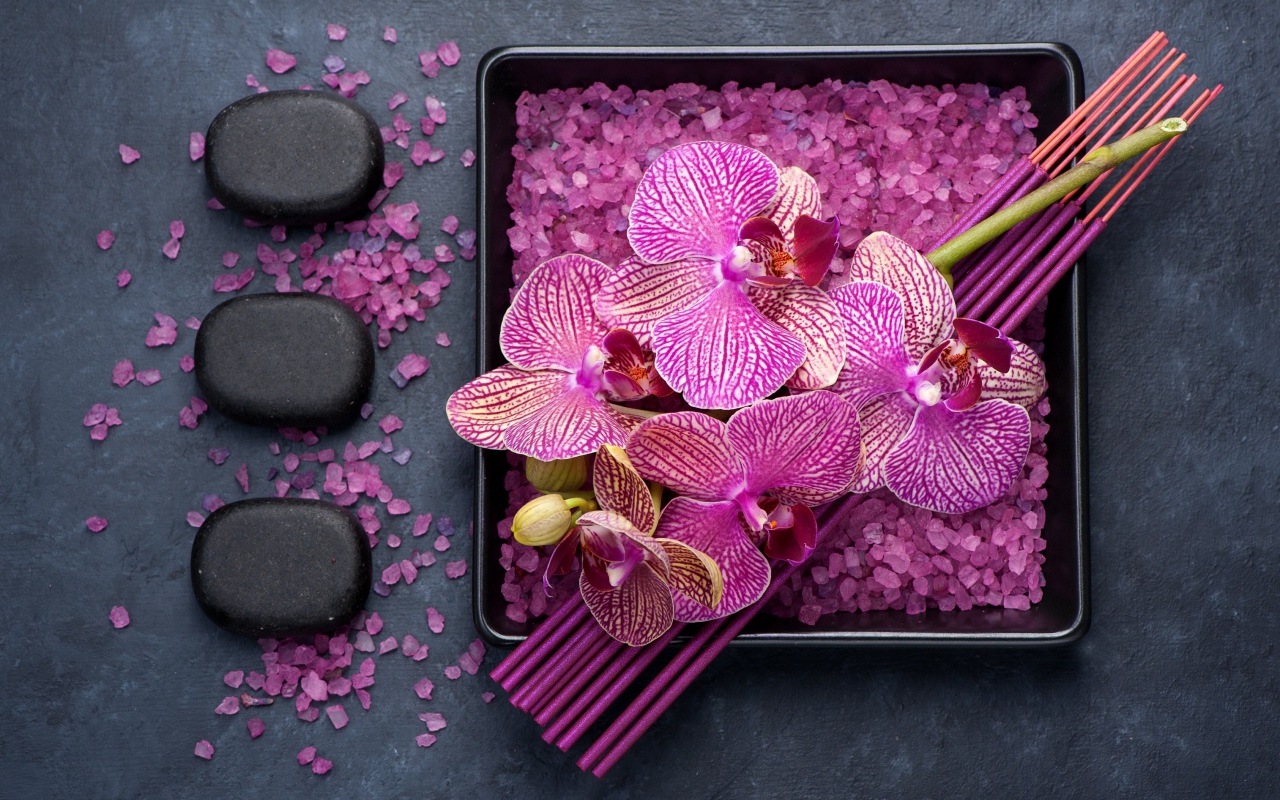 Цветы орхидеи с ароматическими палочками, камнями и солью