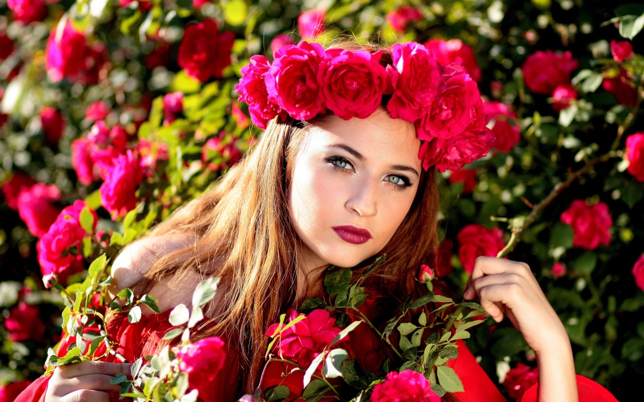 Красивая девушка с венком из красных роз на голове 