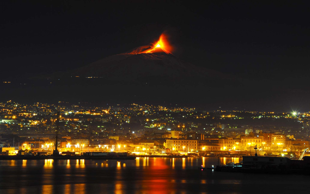 Пробуждение вулкана Этна на фоне ночного города 