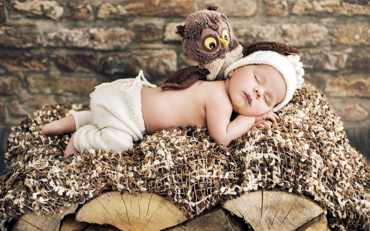 Грудной ребенок спит рядом с игрушкой совой
