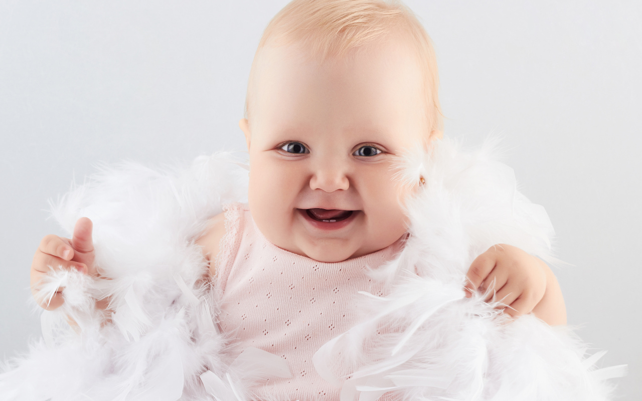 Забавная улыбающаяся маленькая девочка в белых перьях
