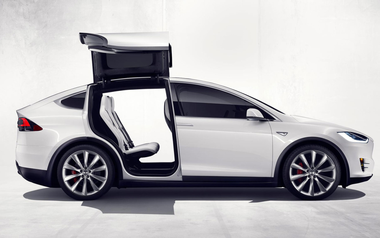Белый электромобиль Тесла с открытыми дверями  