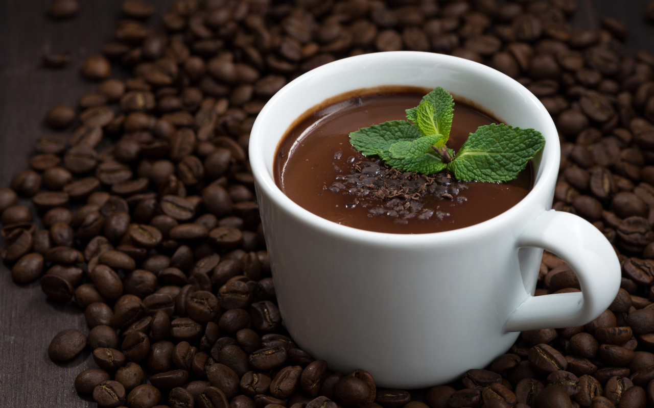 Белая чашка горячего шоколада стоит на кофейных зернах