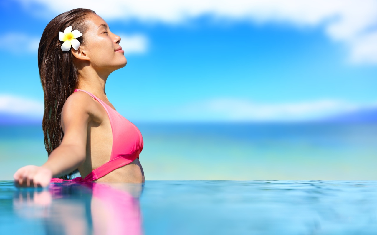Девушка в розовом купальнике стоит в воде на солнце