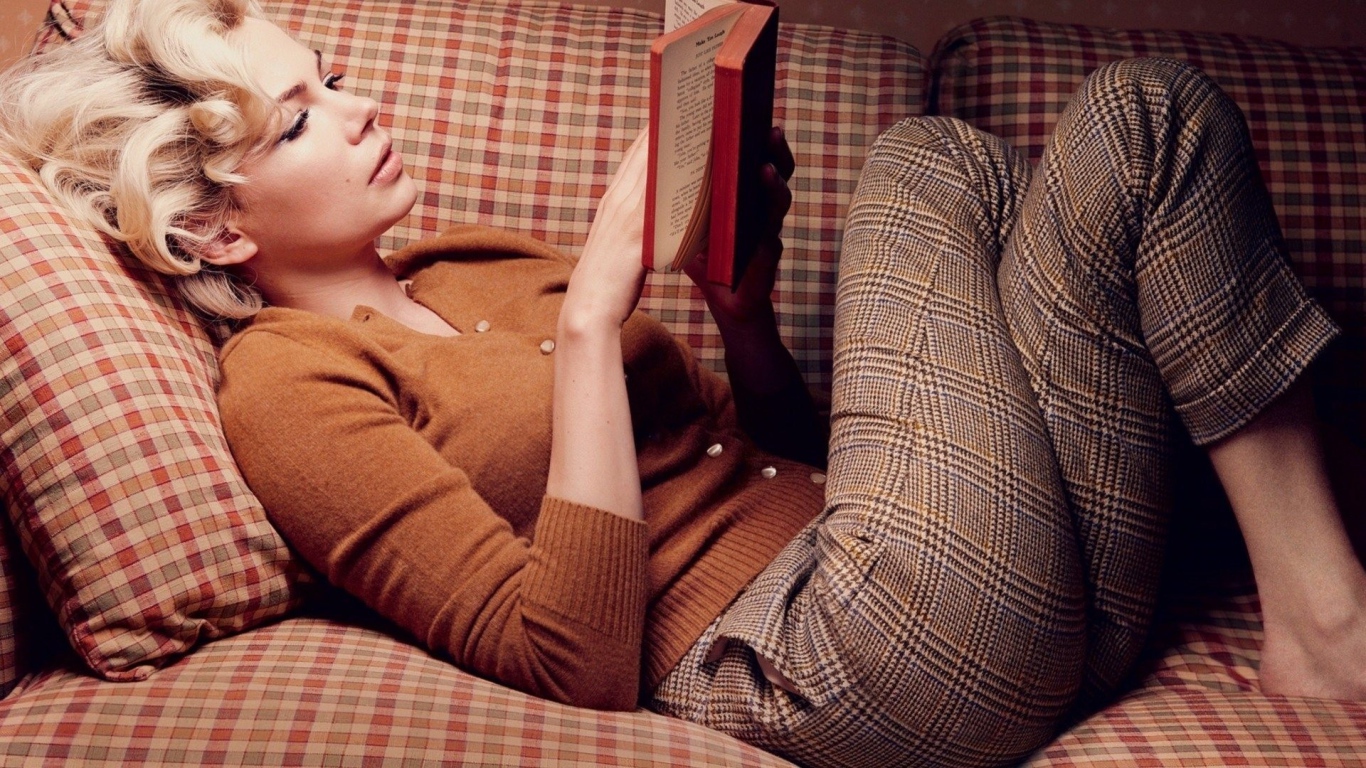 Девушка читает книгу лежа на диване