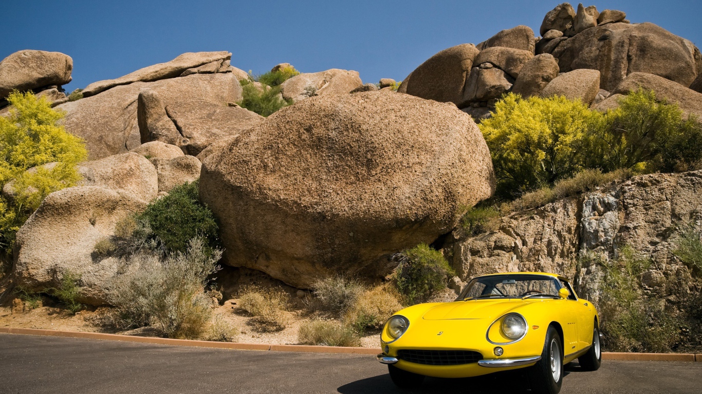 Старый желтый Ferrari у большого камня