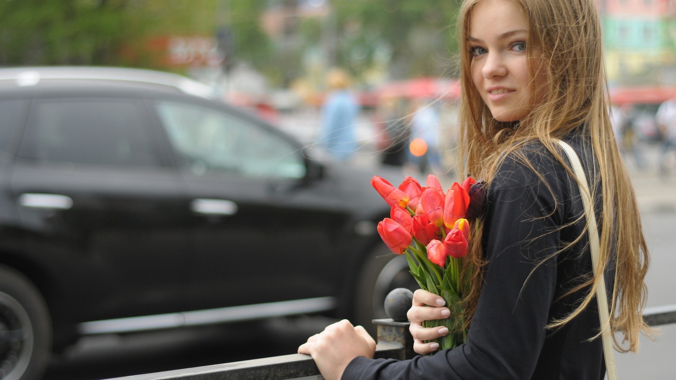 Girl with a bouquet of tulips standing at the fence