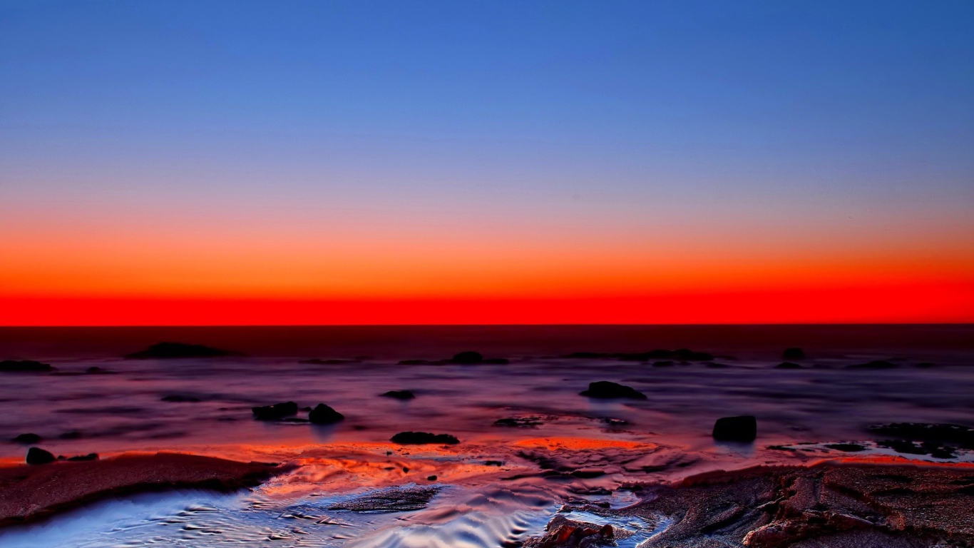 Голубое небо и красный закат на берегу моря