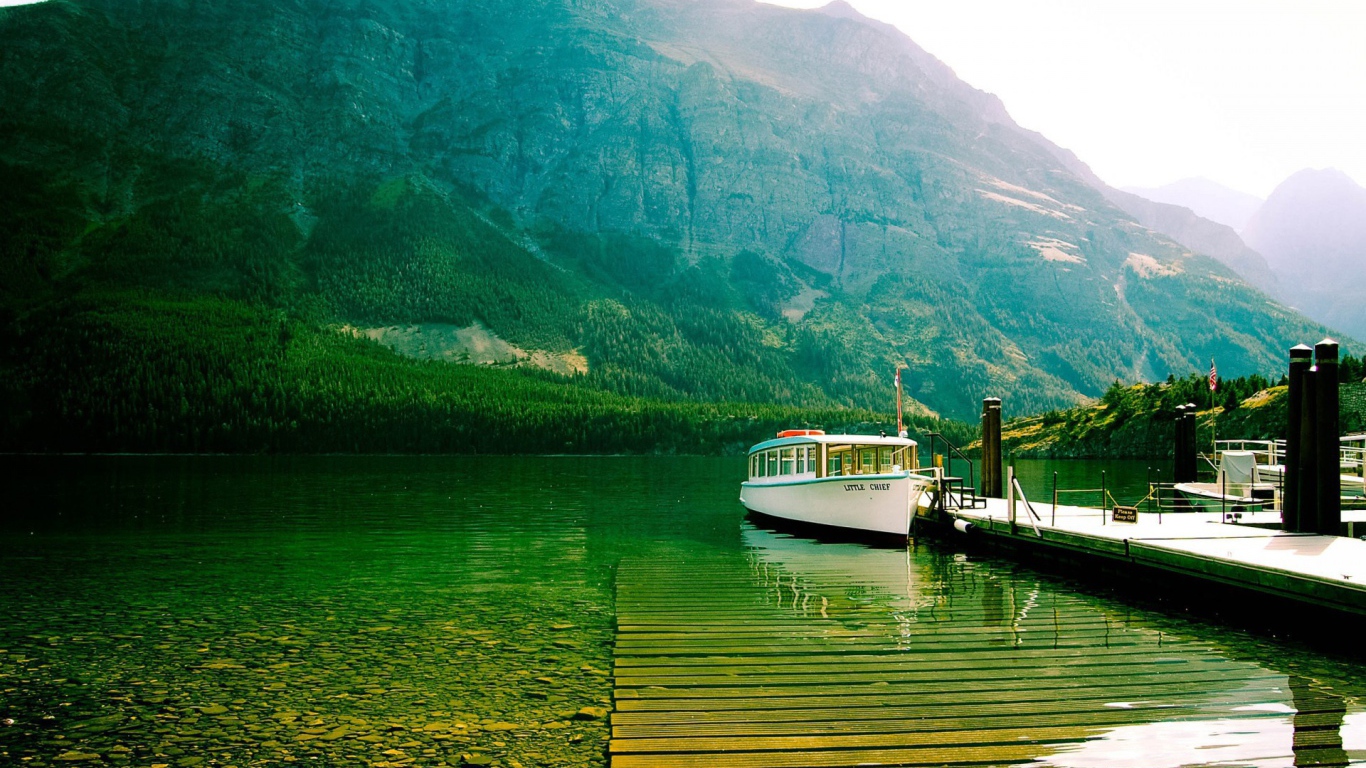 Лодка у причала на зеленой воде горного озера