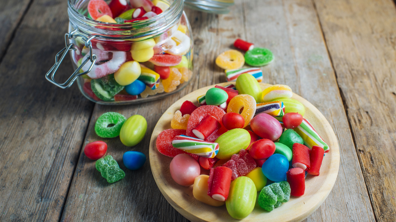 Разноцветные мармеладные конфеты в стеклянной банке на столе