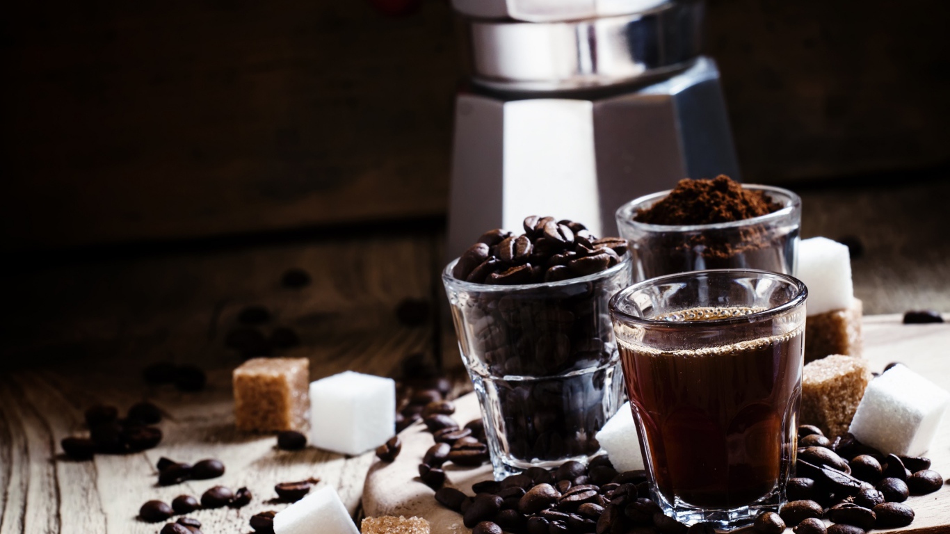 Стаканы с кофе, кофейными зернами и перемолотым кофе на столе с кубиками сахара