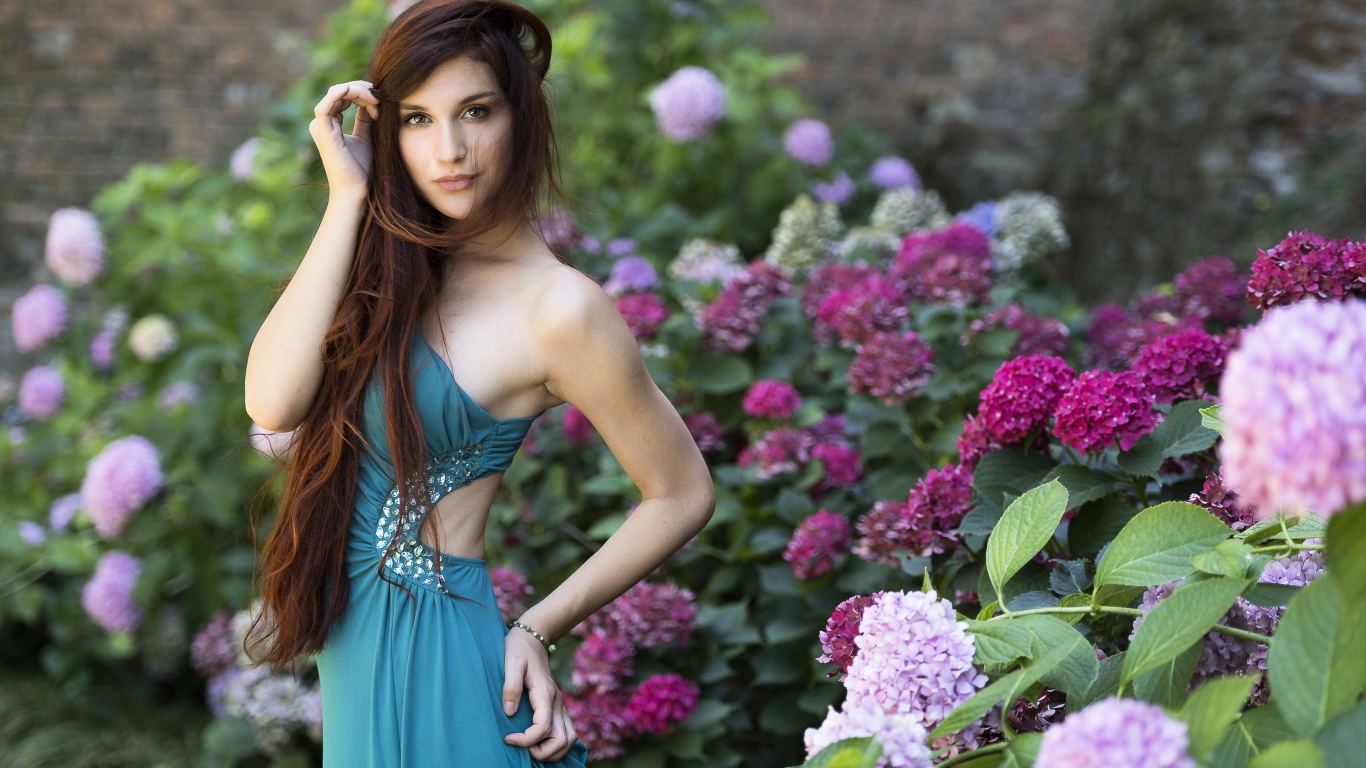 Красивая девушка модель в зеленом платье рядом с цветами гортензии