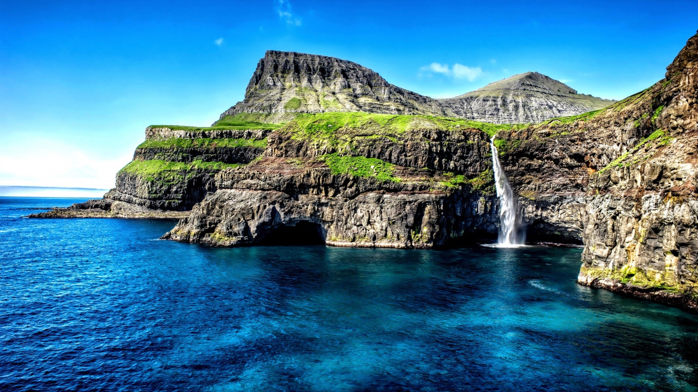 Маленький водопад стекает со скалы в океан, Гавайские острова