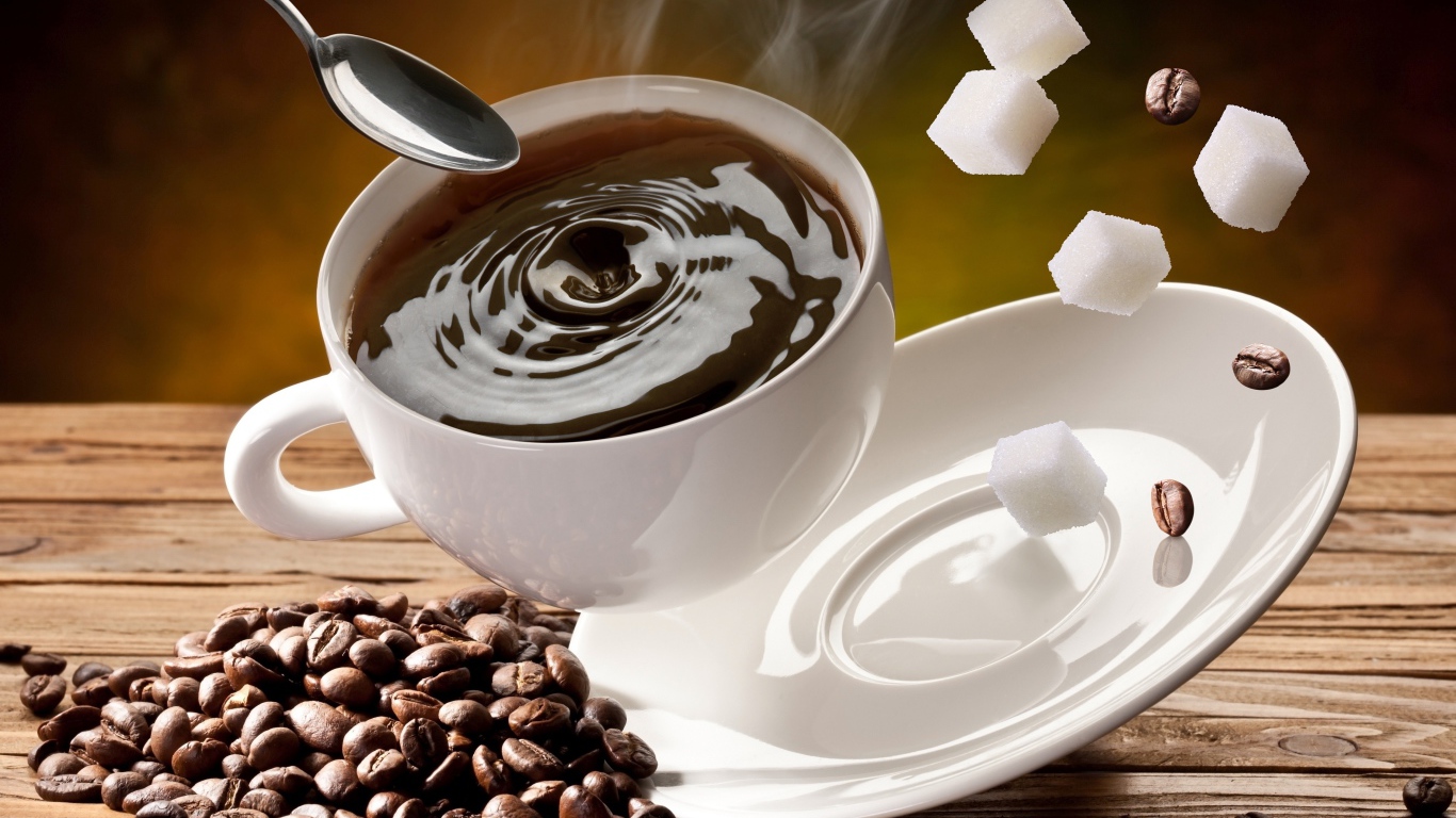 Белая чашка с кофе падает на стол с кофейными зернами