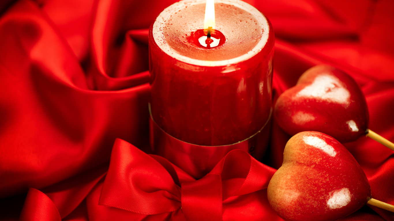 Зажженная свеча с двумя сердечками на красном фоне с бантом