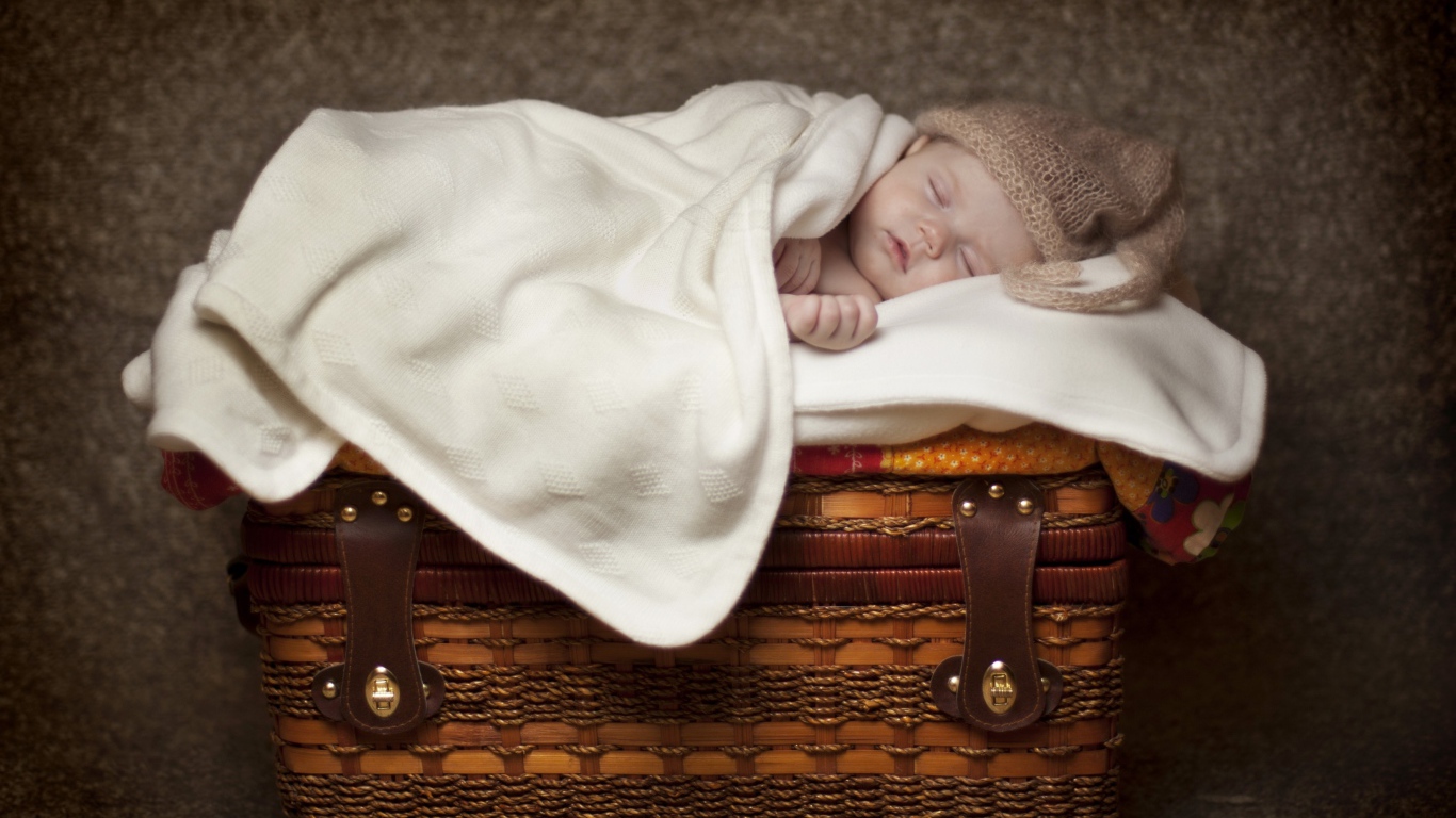 Грудной ребенок спит на плетеной корзине