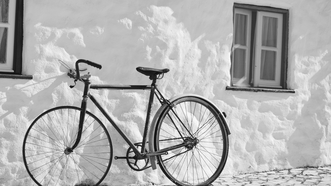 Черный велосипед стоит у белой стены