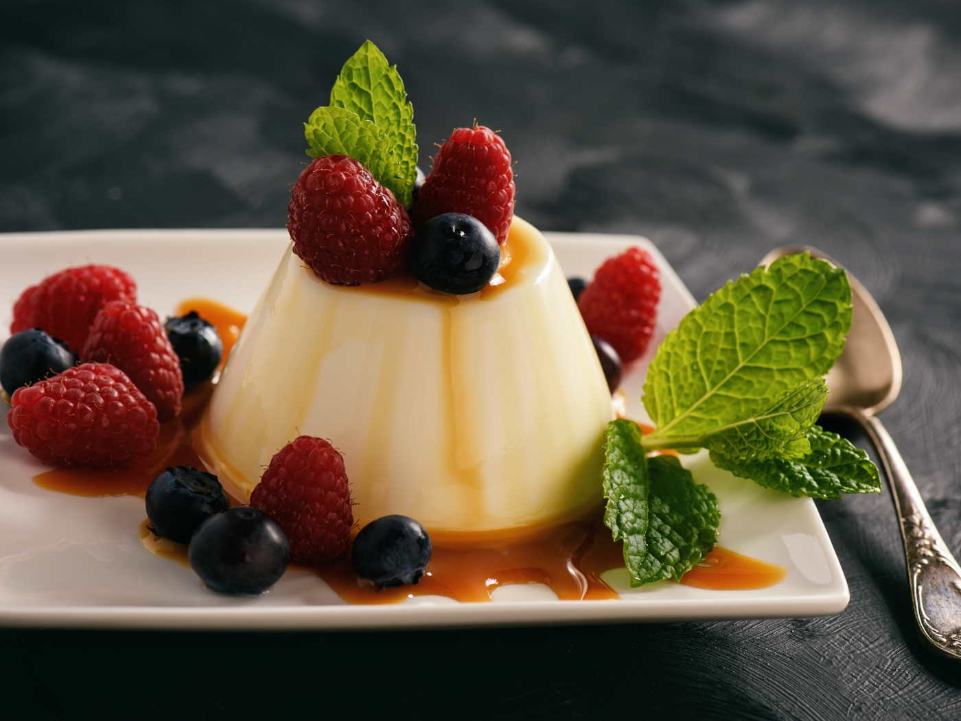 Аппетитный десерт с ягодами клубники и черники на белой тарелке