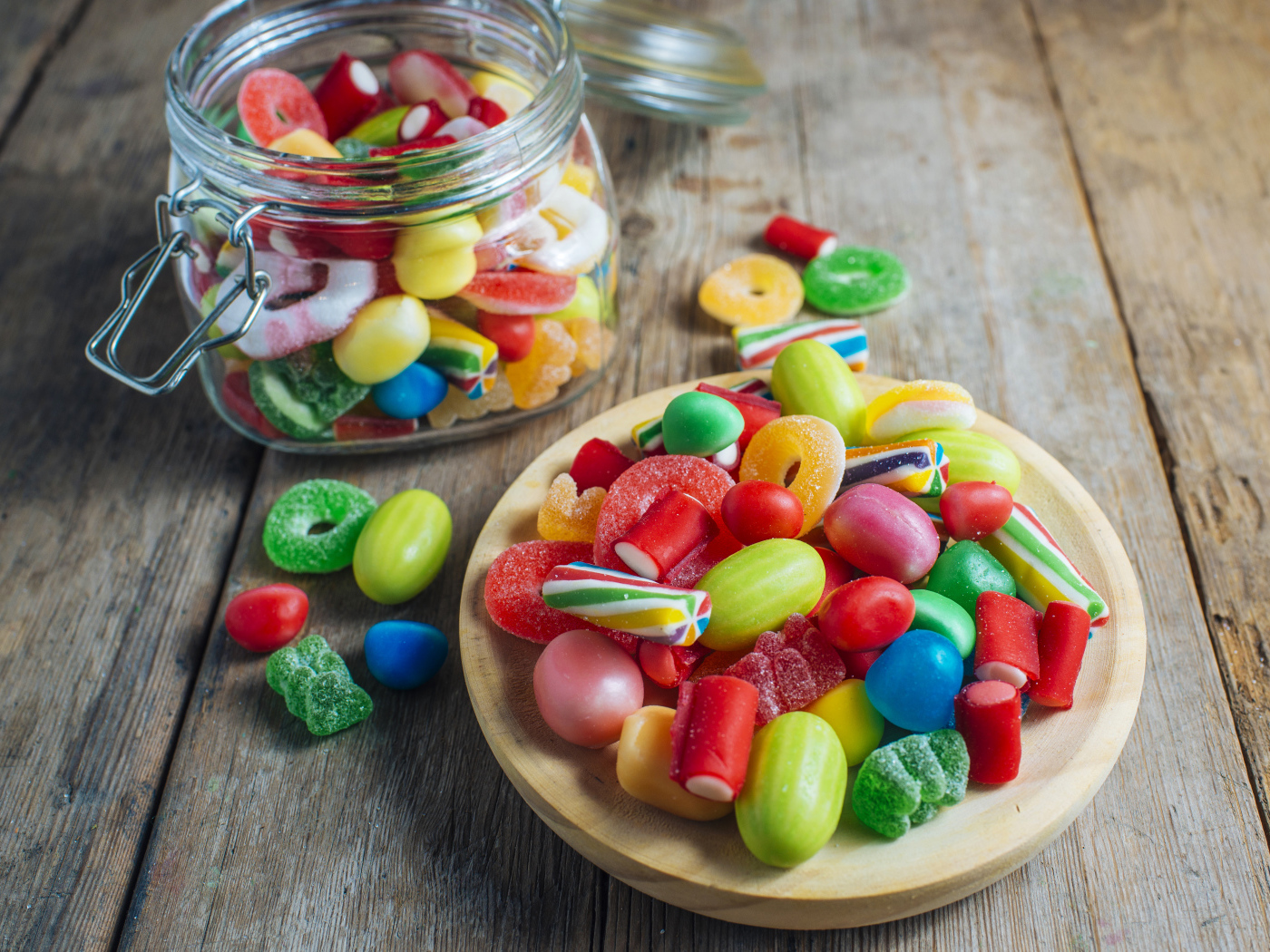 Multicolored marmalade sweets in a glass jar on a table