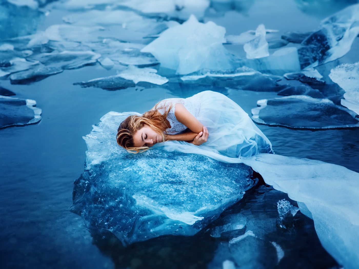 Девушка в красивом белом платье лежит на льдине
