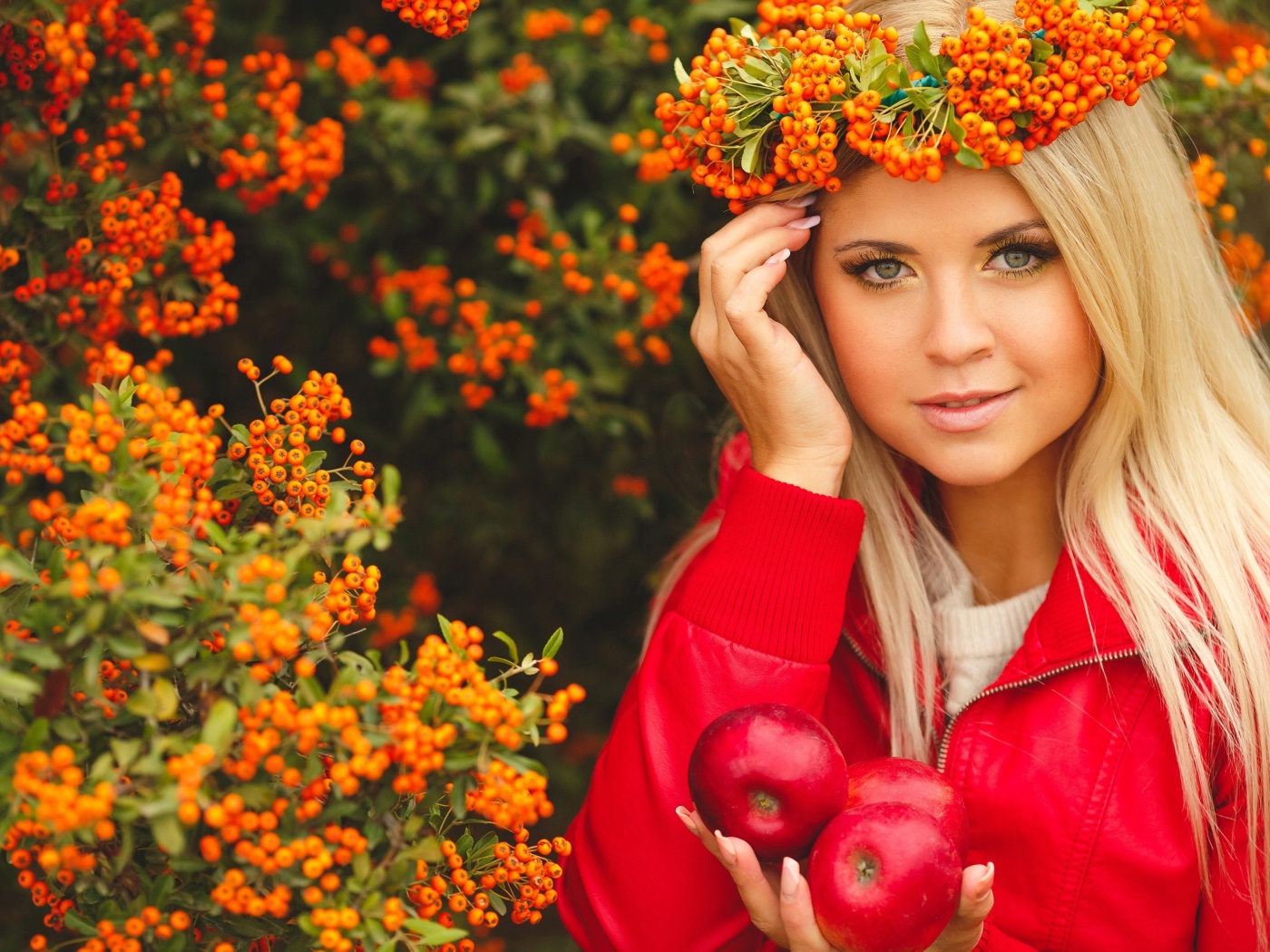Красивая девушка с венком из рябины на голове и с красными яблоками в руках 