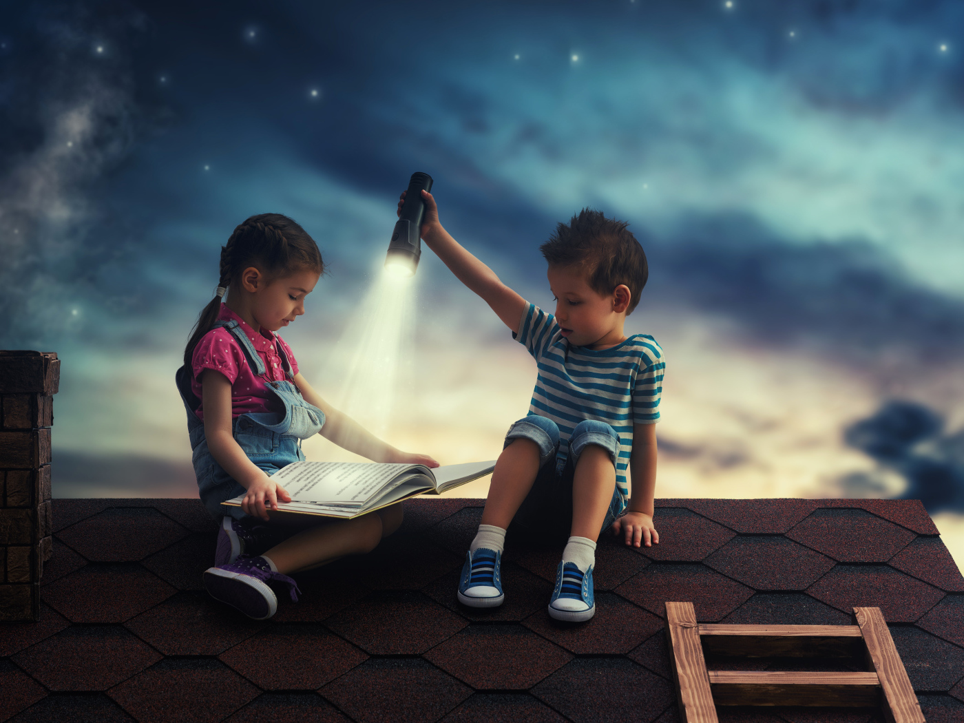 Мальчик и девочка ночью читают книгу на крыше