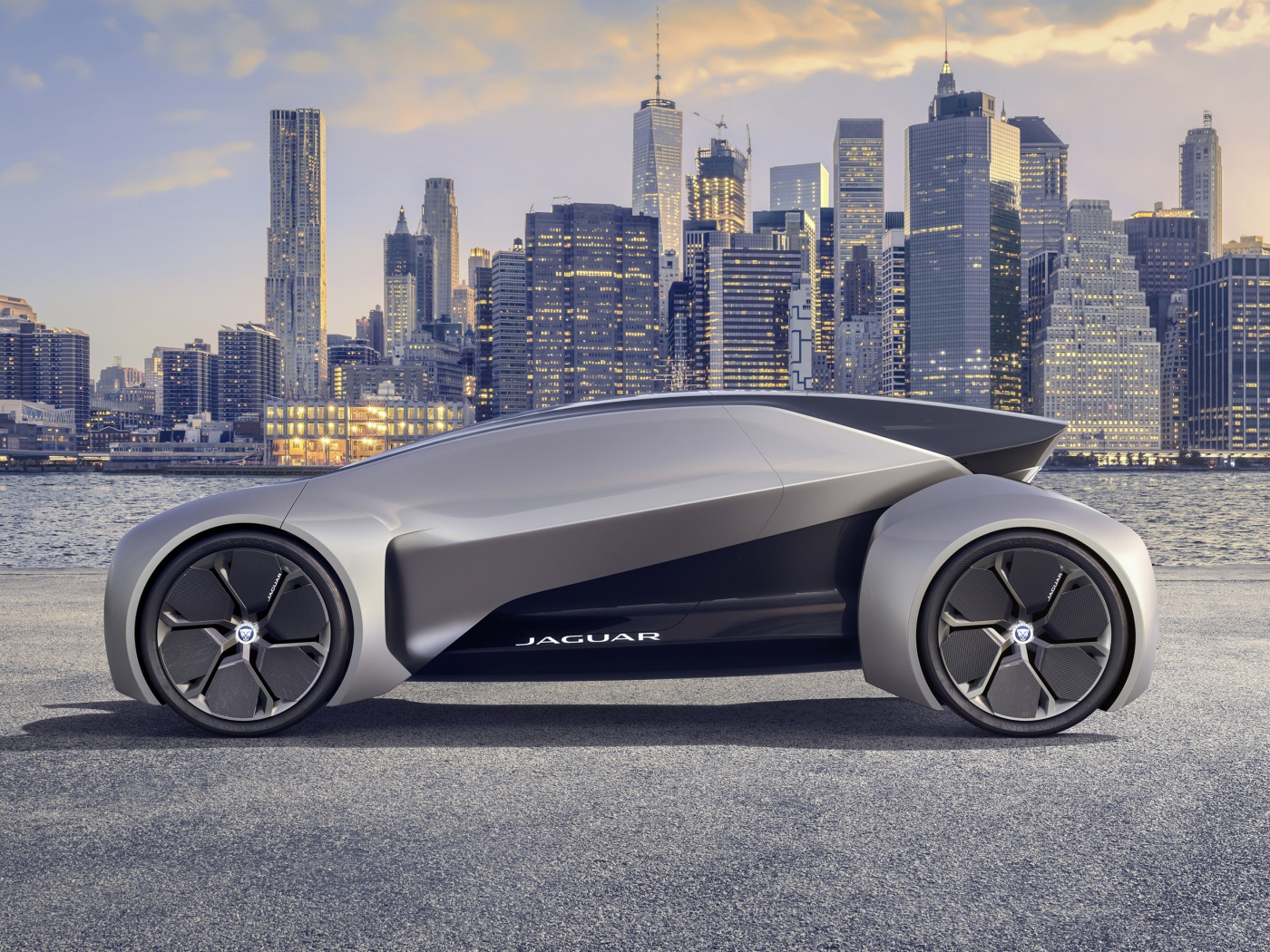 Серебристый электрический автомобиль  Jaguar Future-Type на фоне небоскребов