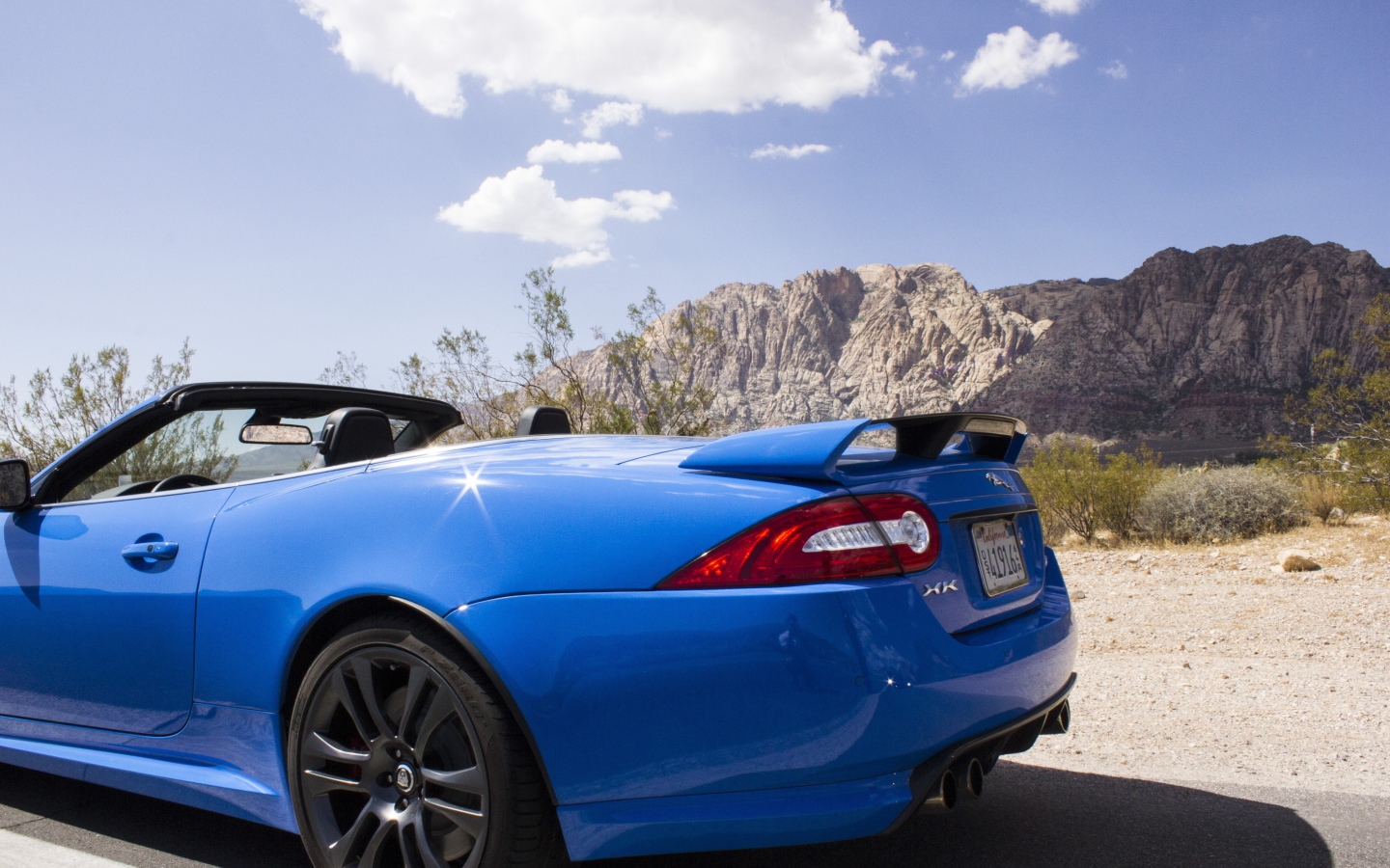 Голубой кабриолет Jaguar на фоне гор