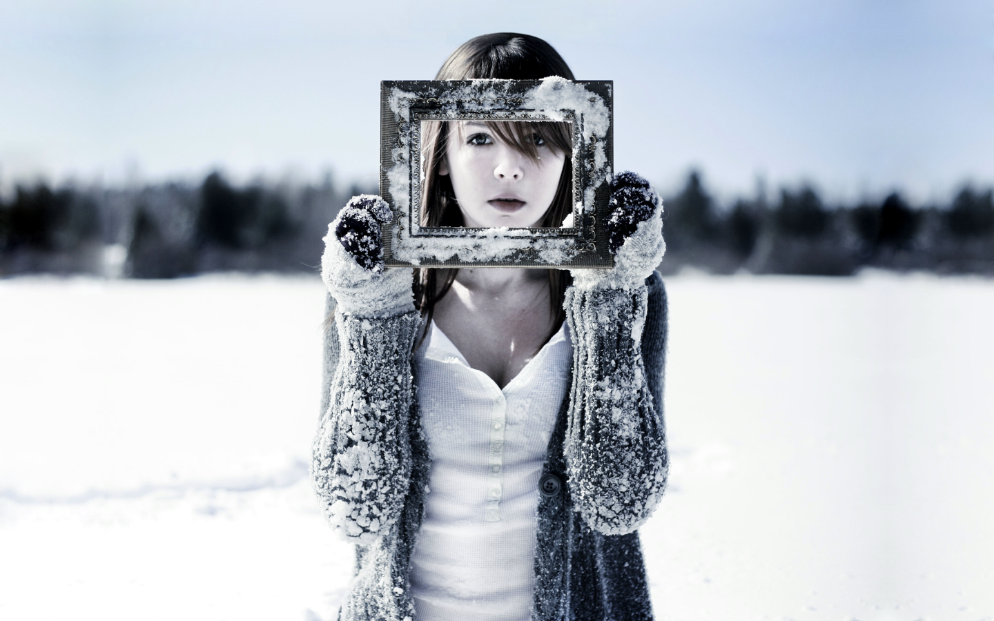 Девушка держит в руках фоторамку в снегу