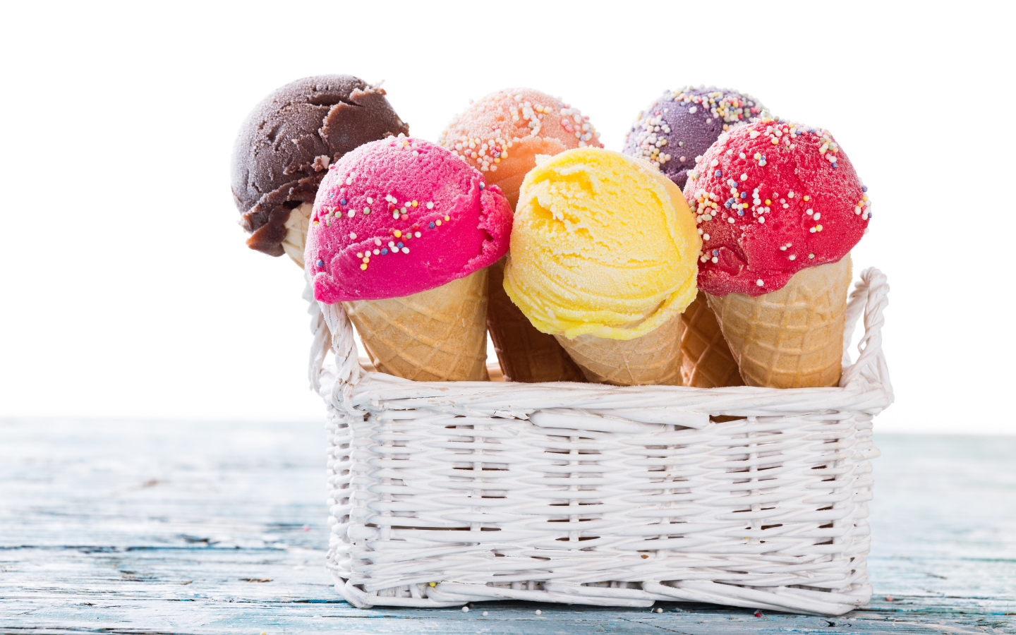 Разноцветное мороженое в вафельных рожках в белой корзине на столе