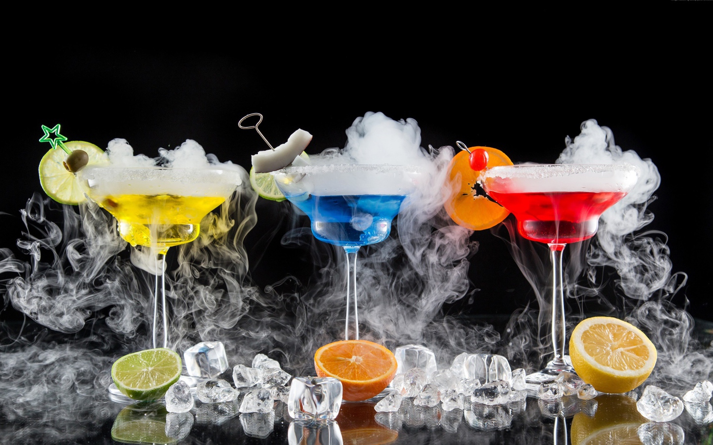 Three alcoholic cocktails with dry ice on a black background