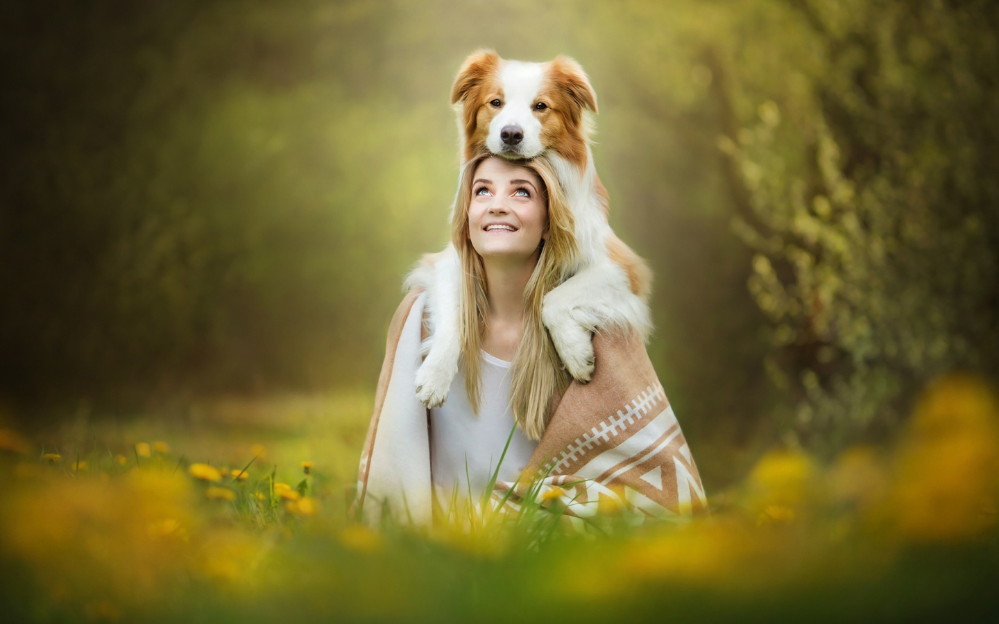 Улыбающаяся девушка с собакой сидят на траве