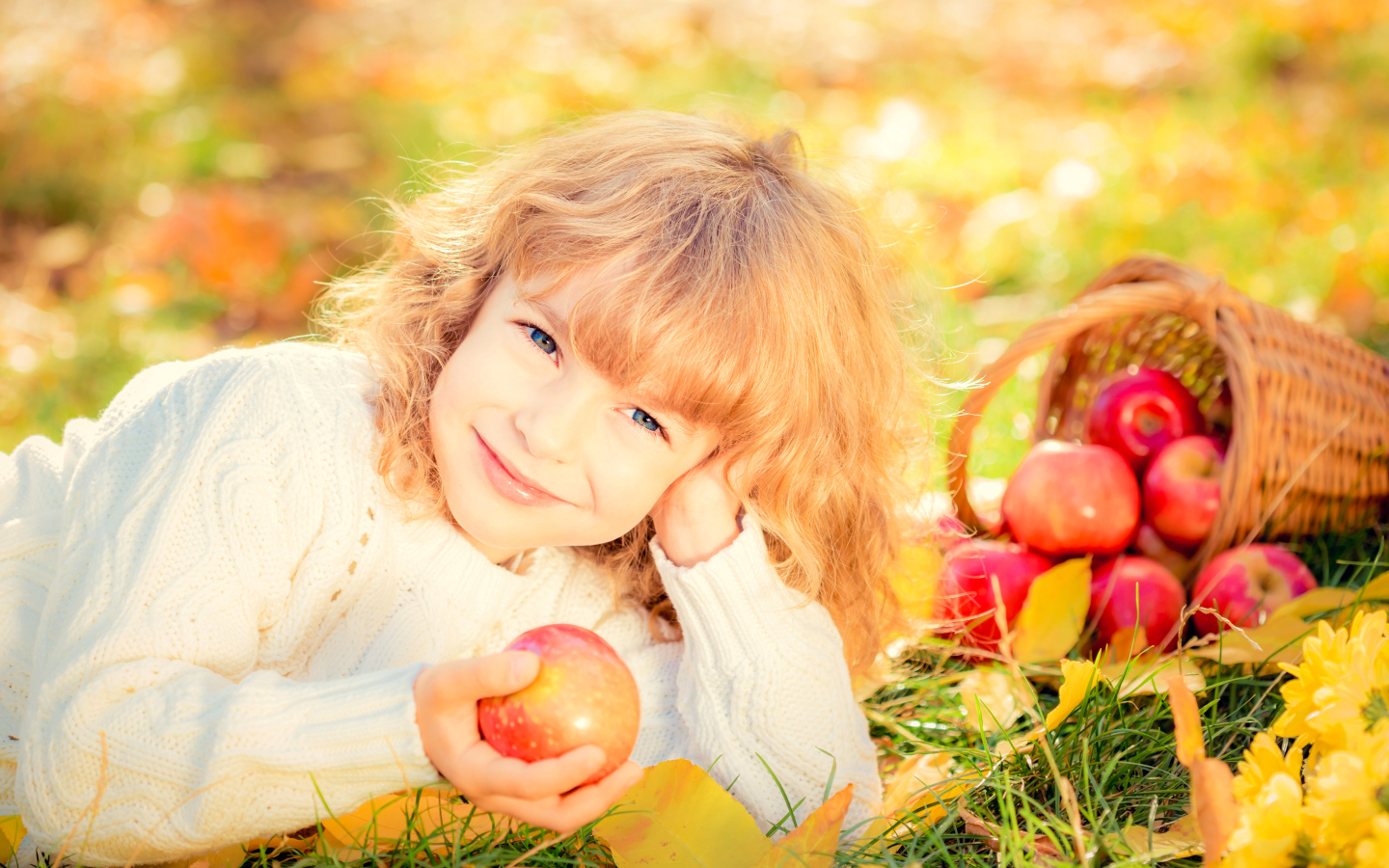 Улыбающаяся рыжеволосая девочка с корзиной красных яблок